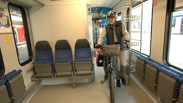 Mann schiebt Fahrrad in einem Zug | Bild: BR